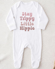 A white onesie with the text "Stay Trippy Little Hippie" printed on it.