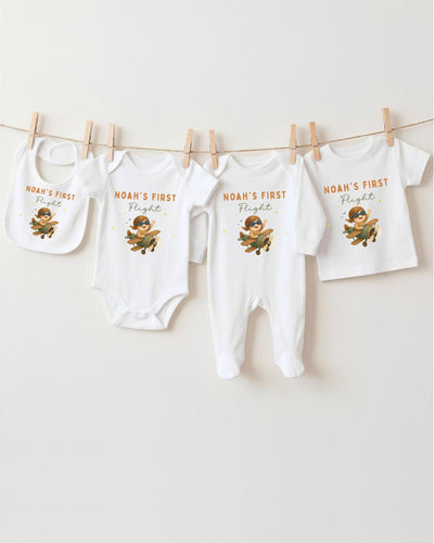 A collection of baby clothes, including onesies and bibs, hanging on a clothesline.
