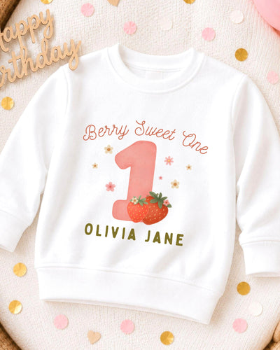 A white sweatshirt with a personalized design for a first birthday celebration.