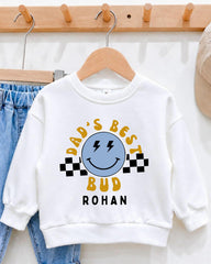 A white sweatshirt with a graphic design and text printed on it, hanging on a wooden hanger.