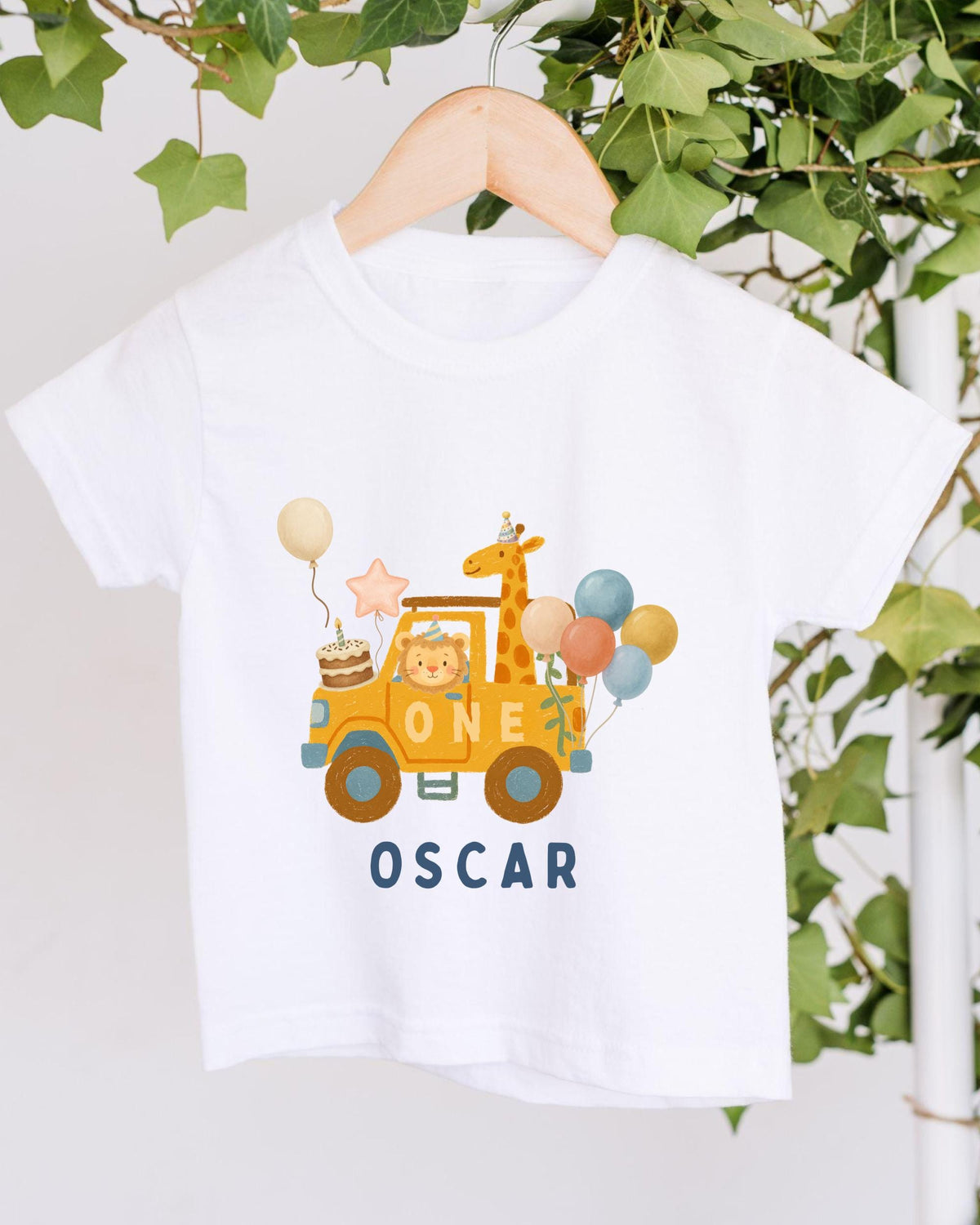 A white t-shirt with a graphic design featuring a yellow car, a giraffe, and balloons, along with the text "ONE OSCAR".