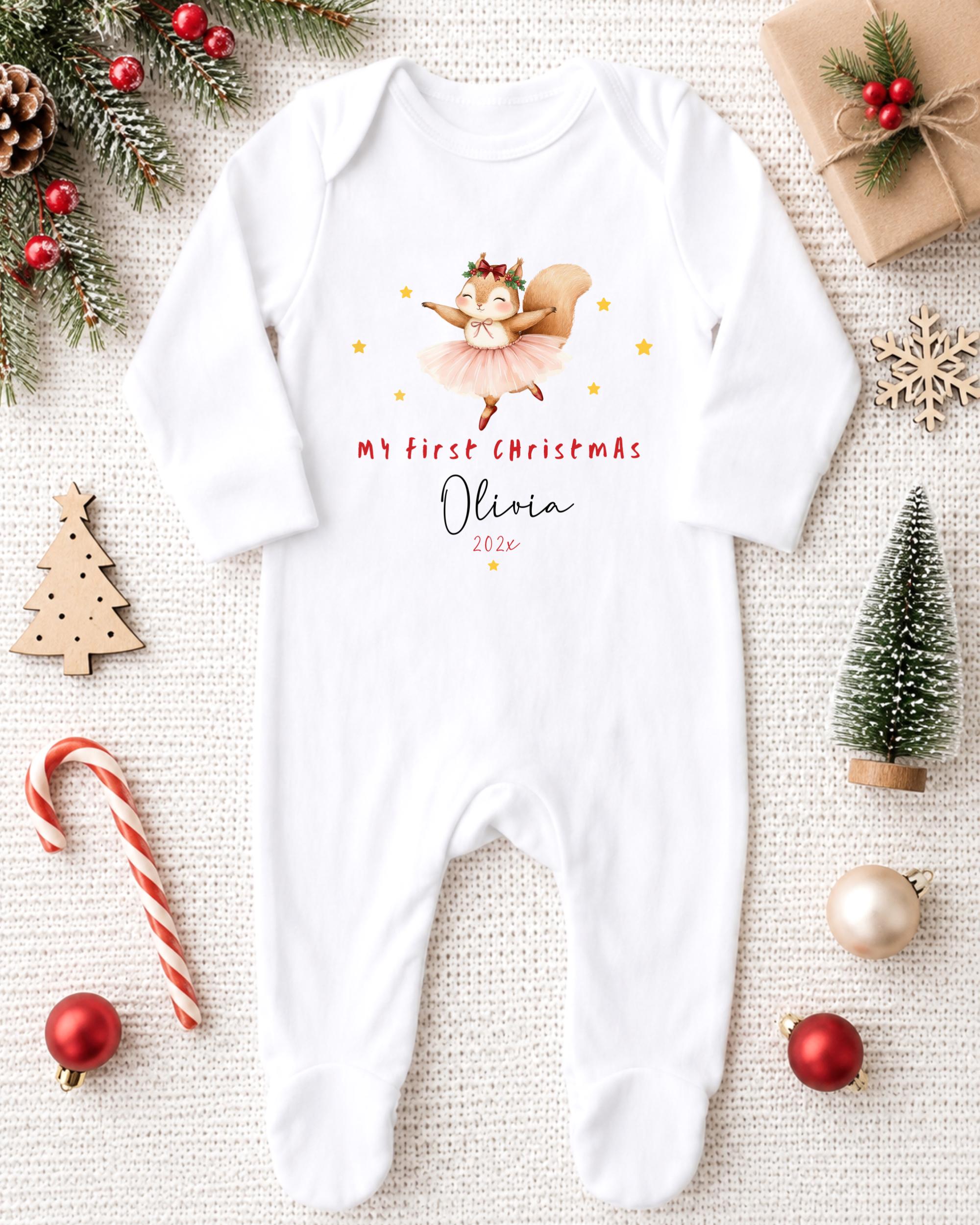 A white onesie with a cartoon squirrel and the text "My first Christmas Olivia" printed on it, along with a small Christmas tree and ornaments.