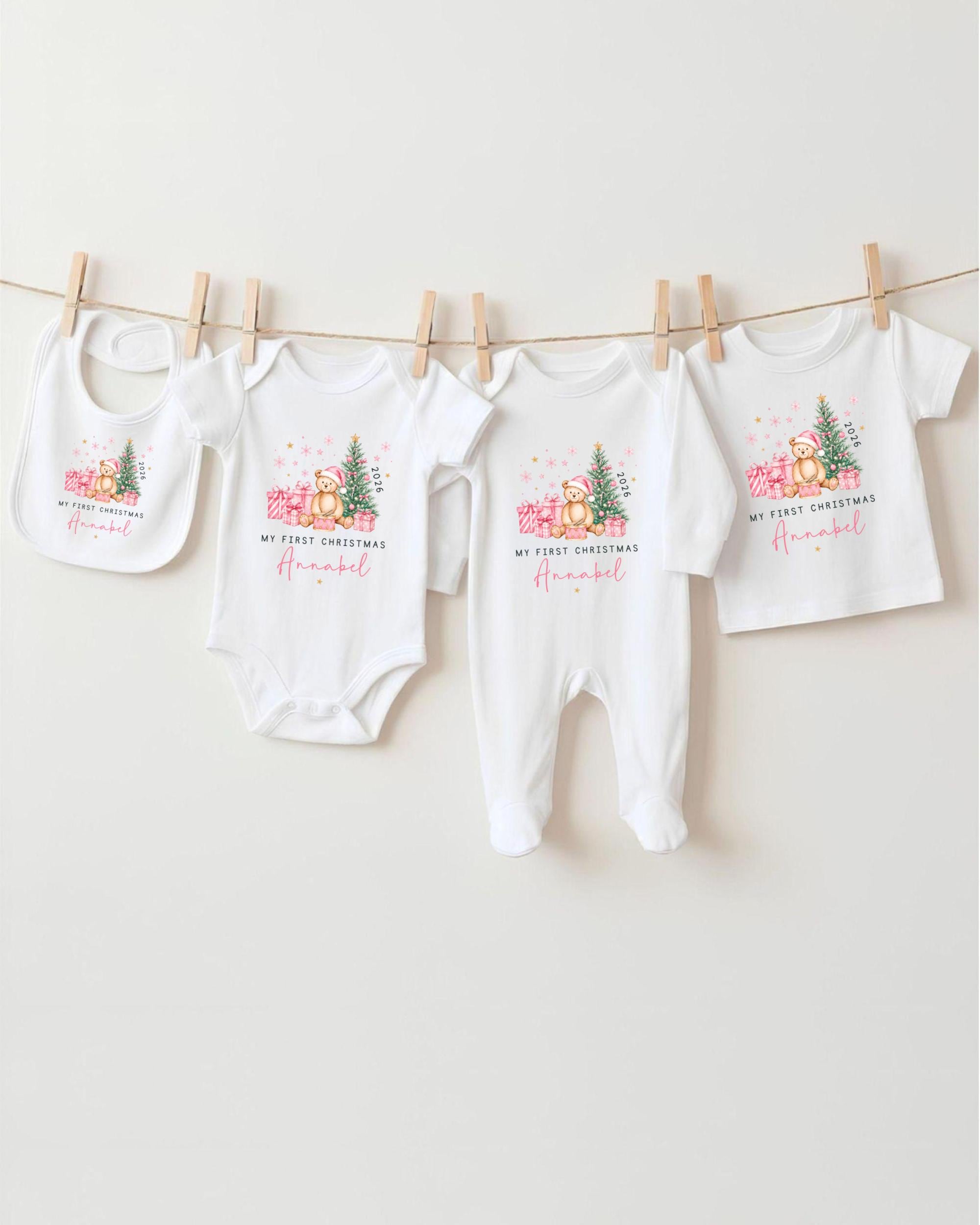 A collection of four white baby clothes, including onesies and bibs, hanging on a clothesline.
