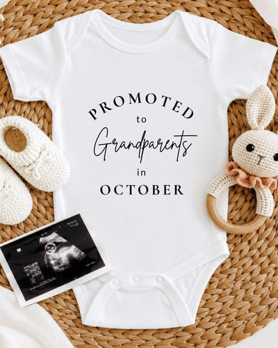 Personalisable white Baby Vest with black 'Promoted to Grandparents in October' curved serif and script lettering.