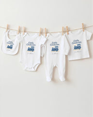 A row of baby clothes, including onesies and pants, hanging on a clothesline.
