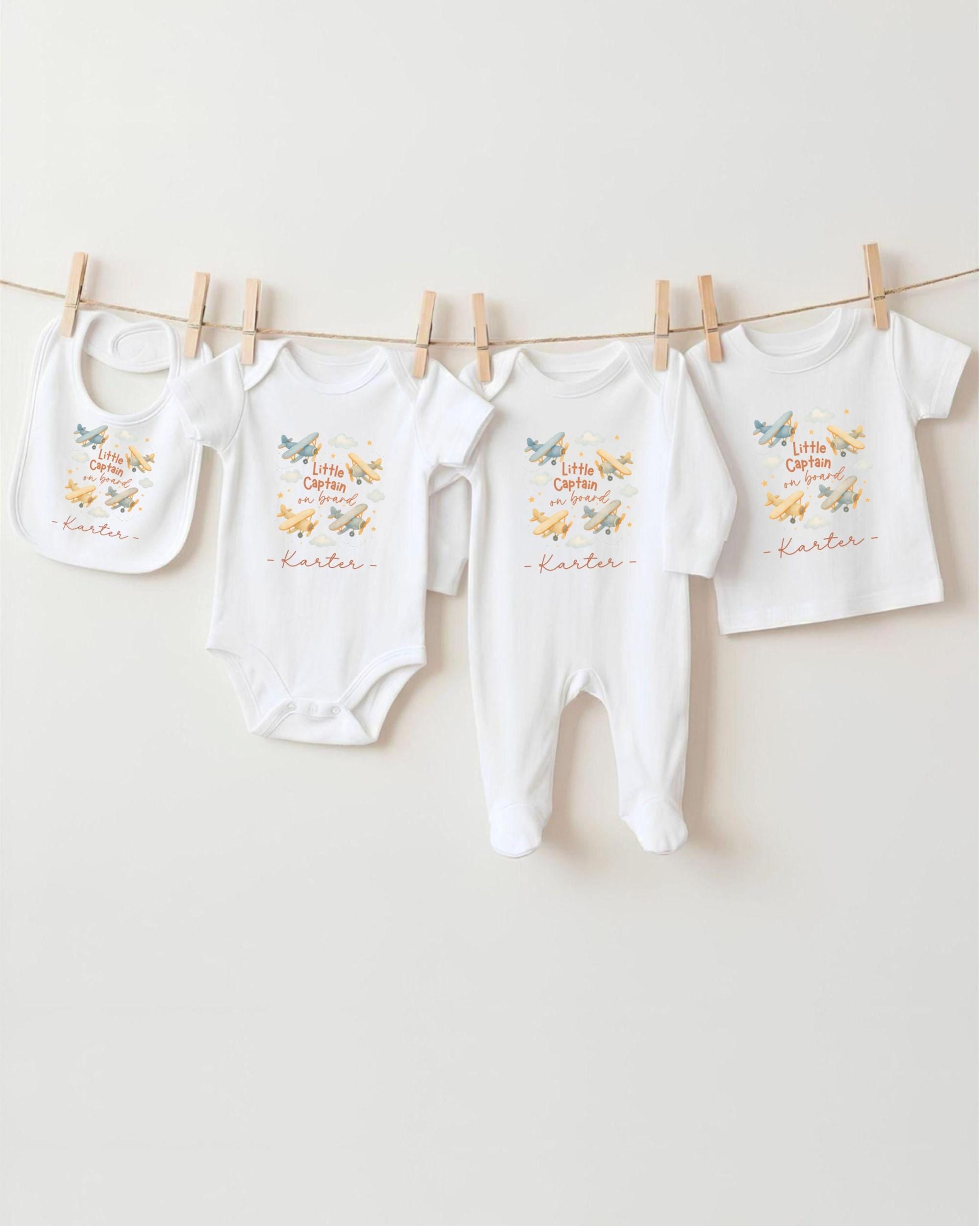 A collection of baby clothes, including onesies and pants, hanging on a clothesline.