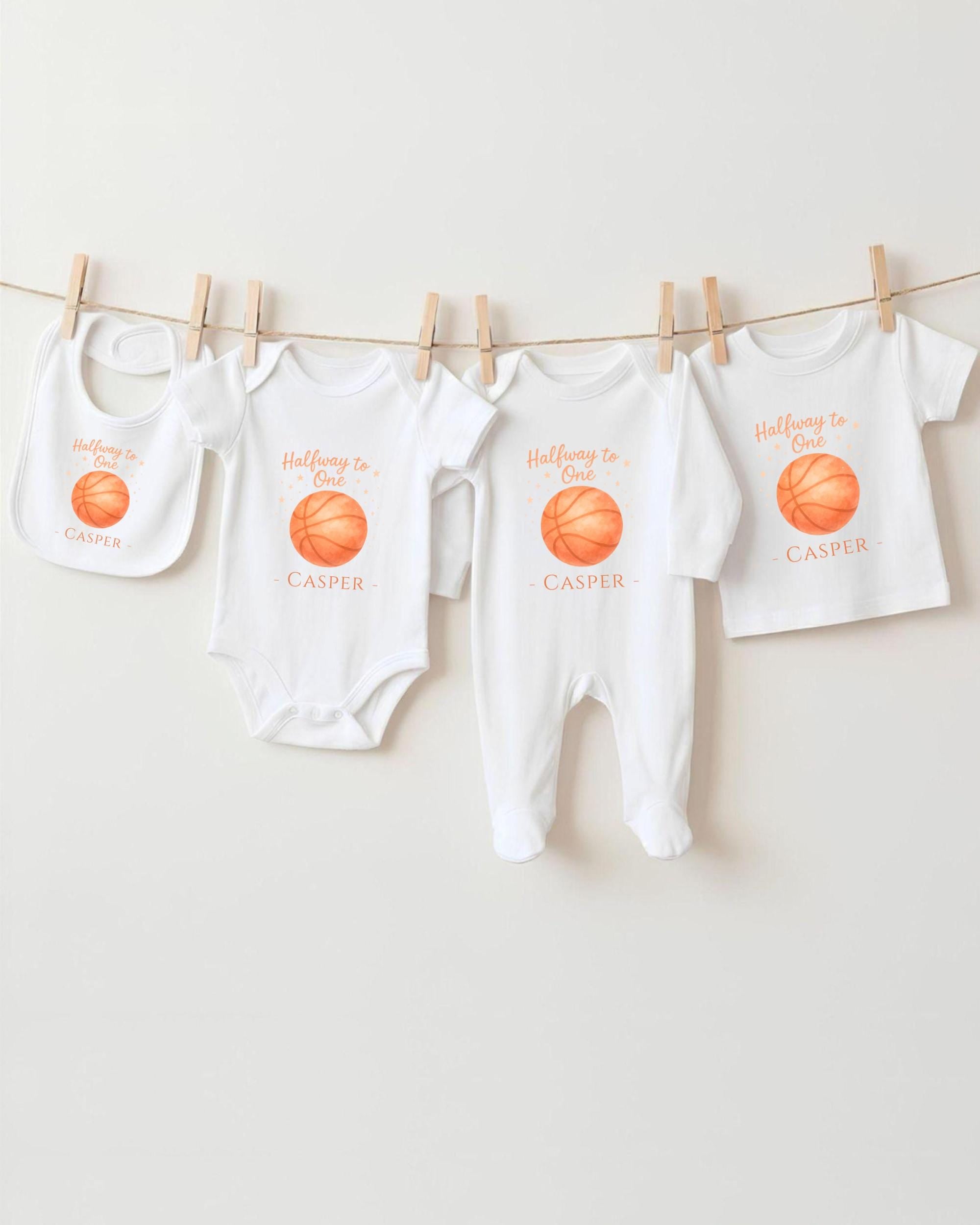 A collection of white baby clothes, including onesies and bibs, hanging on a clothesline.