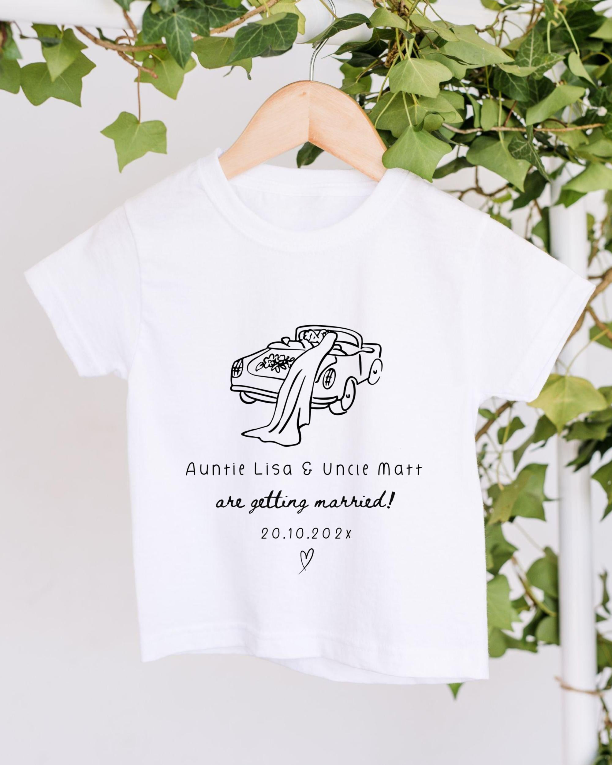 A white t-shirt with a graphic design of a couple in a car, along with text that reads "Auntie Lisa & Uncle Matt are getting married! 20.10.2021".