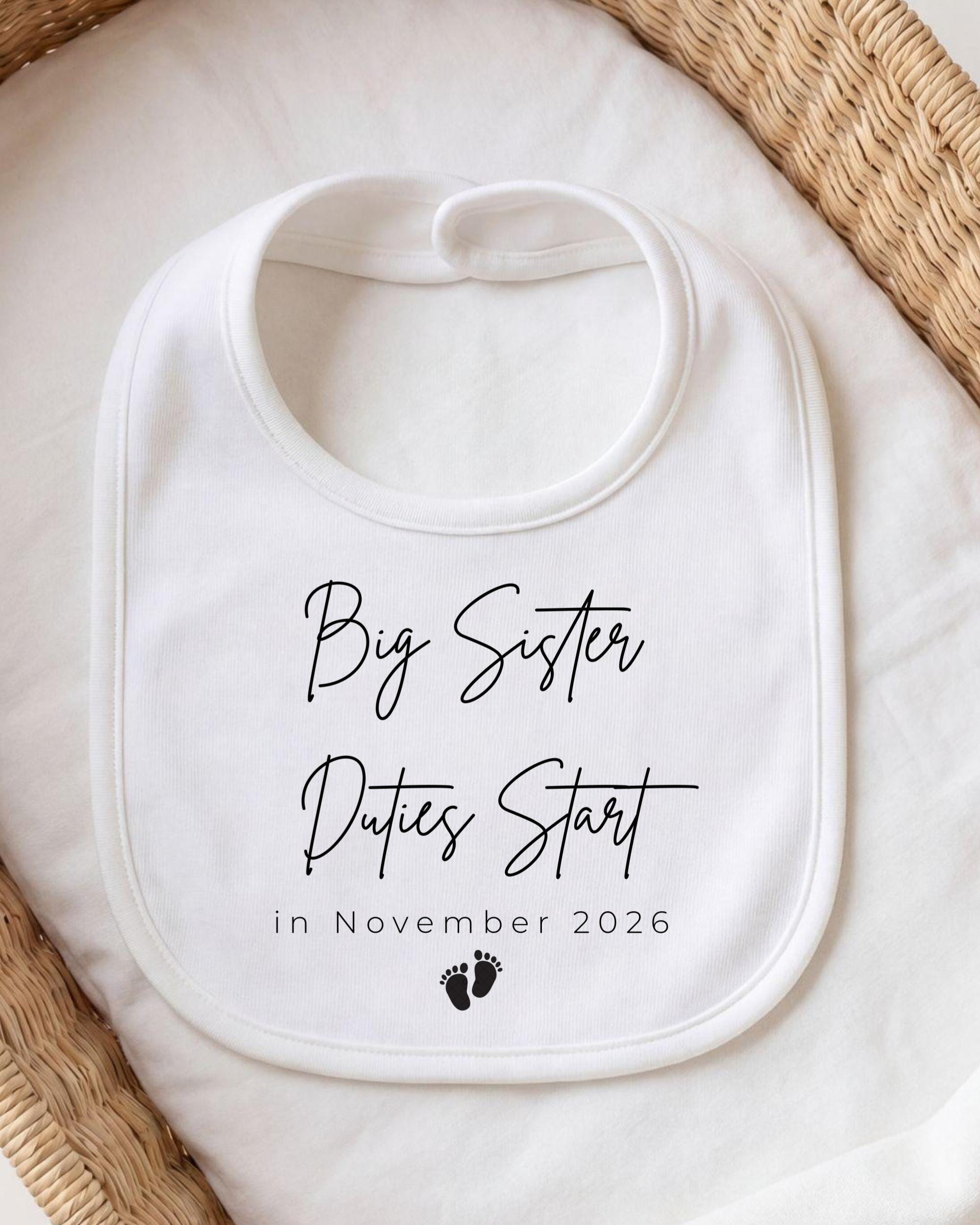 A white bib with black text and a small footprint graphic, placed on a white cloth.