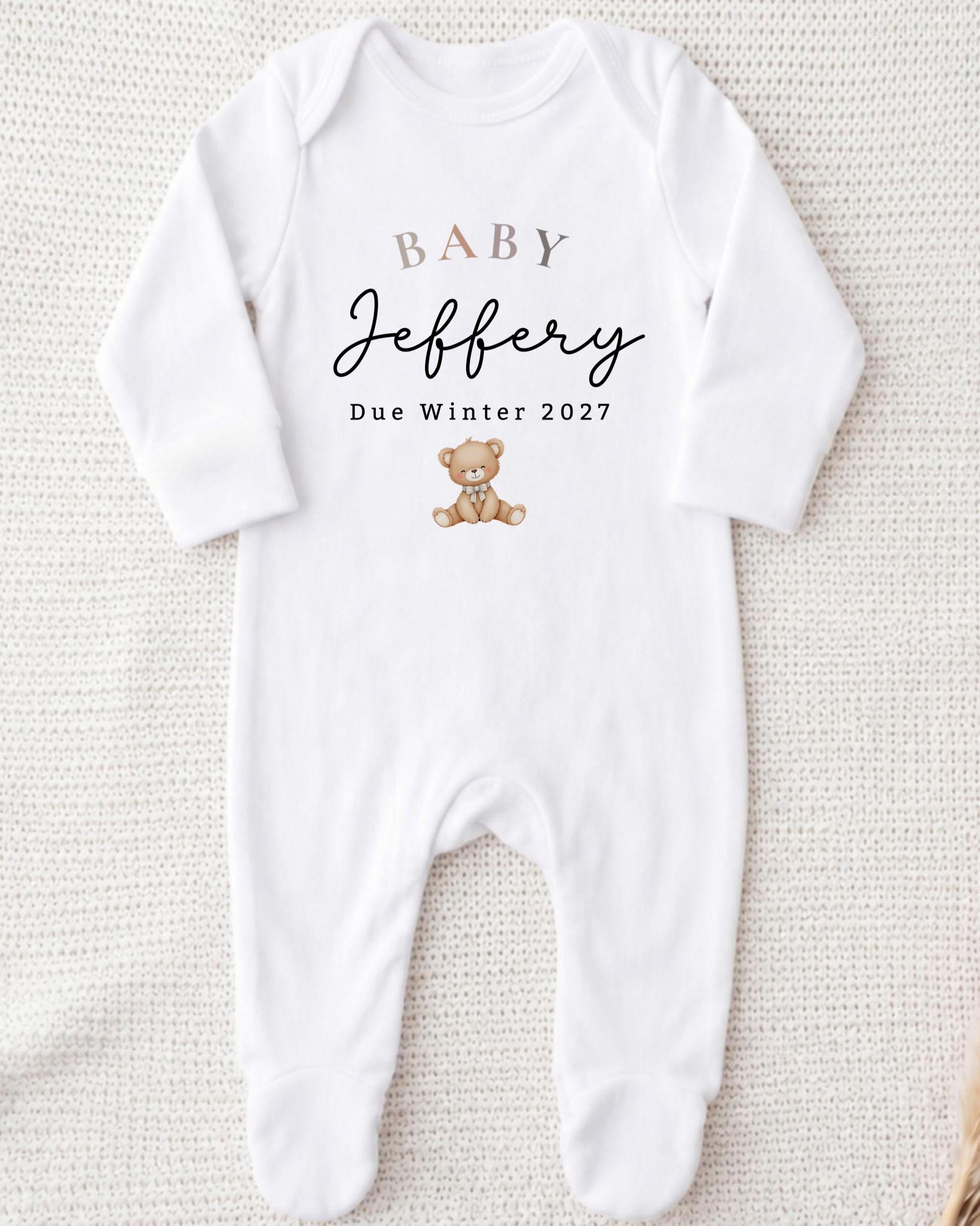 A white onesie with text and a teddy bear graphic printed on it.