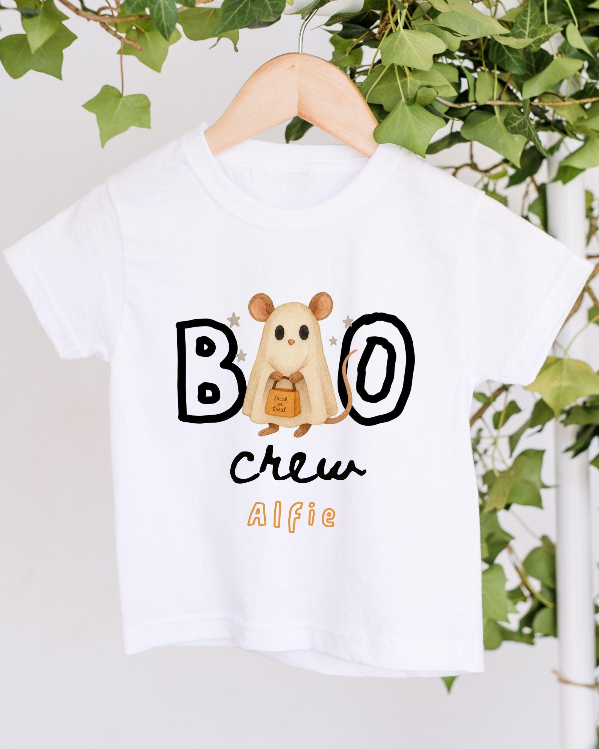 A white t-shirt with a cartoon mouse and the text "BOO" and "CREW AIFIE" printed on it, hanging on a wooden hanger.