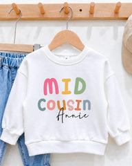 A white sweatshirt with the text "MID COUSIN Annie" printed on it, hanging on a wooden hanger.