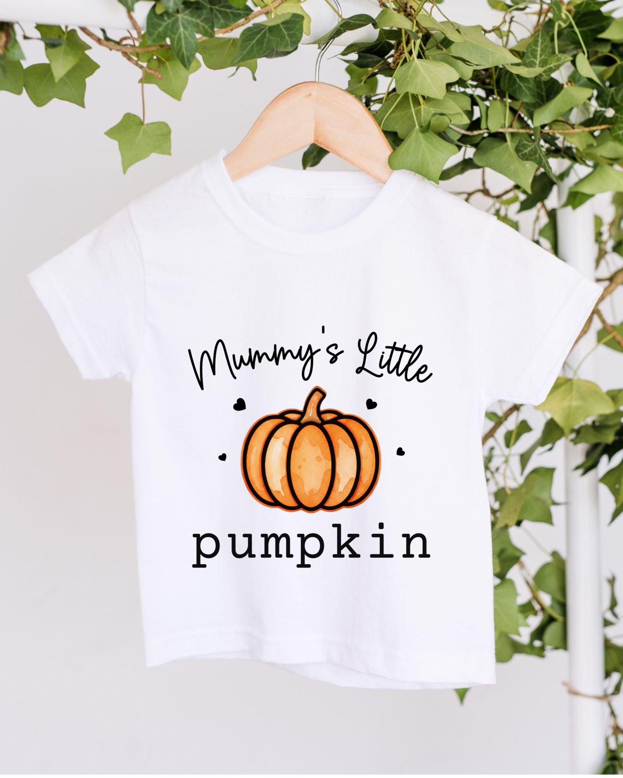 A white t-shirt with a graphic design of a pumpkin and the text "Mummy's Little pumpkin" printed on it, hanging on a wooden hanger.
