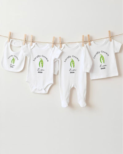 A row of white baby clothes with the text "Locally Grown" printed on them, hanging on a clothesline.