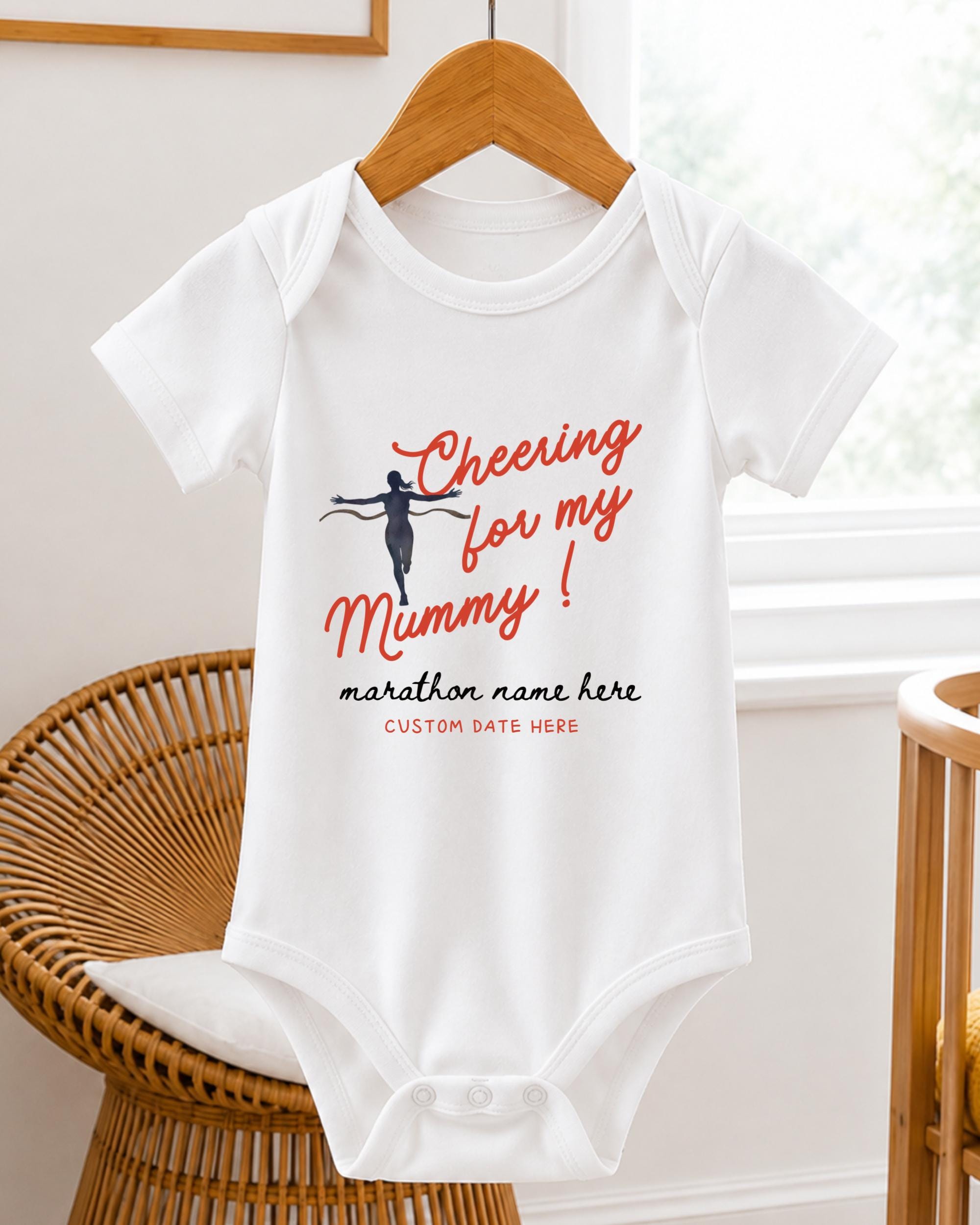 A white baby onesie with a graphic design and text printed on it, hanging on a wooden hanger.