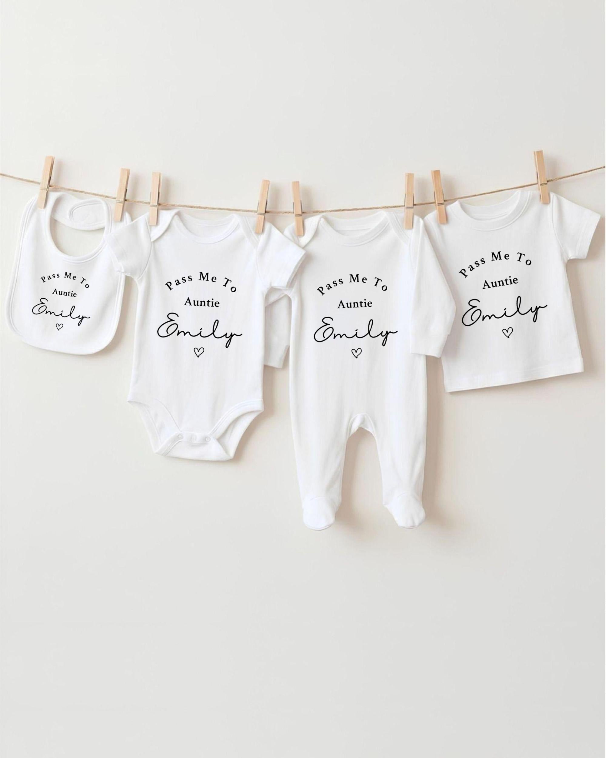 A row of white baby clothes with personalized names printed on them, hanging on a clothesline.
