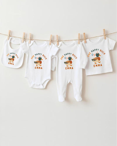 A row of four white baby clothes with a happy duck design, hanging on a clothesline.