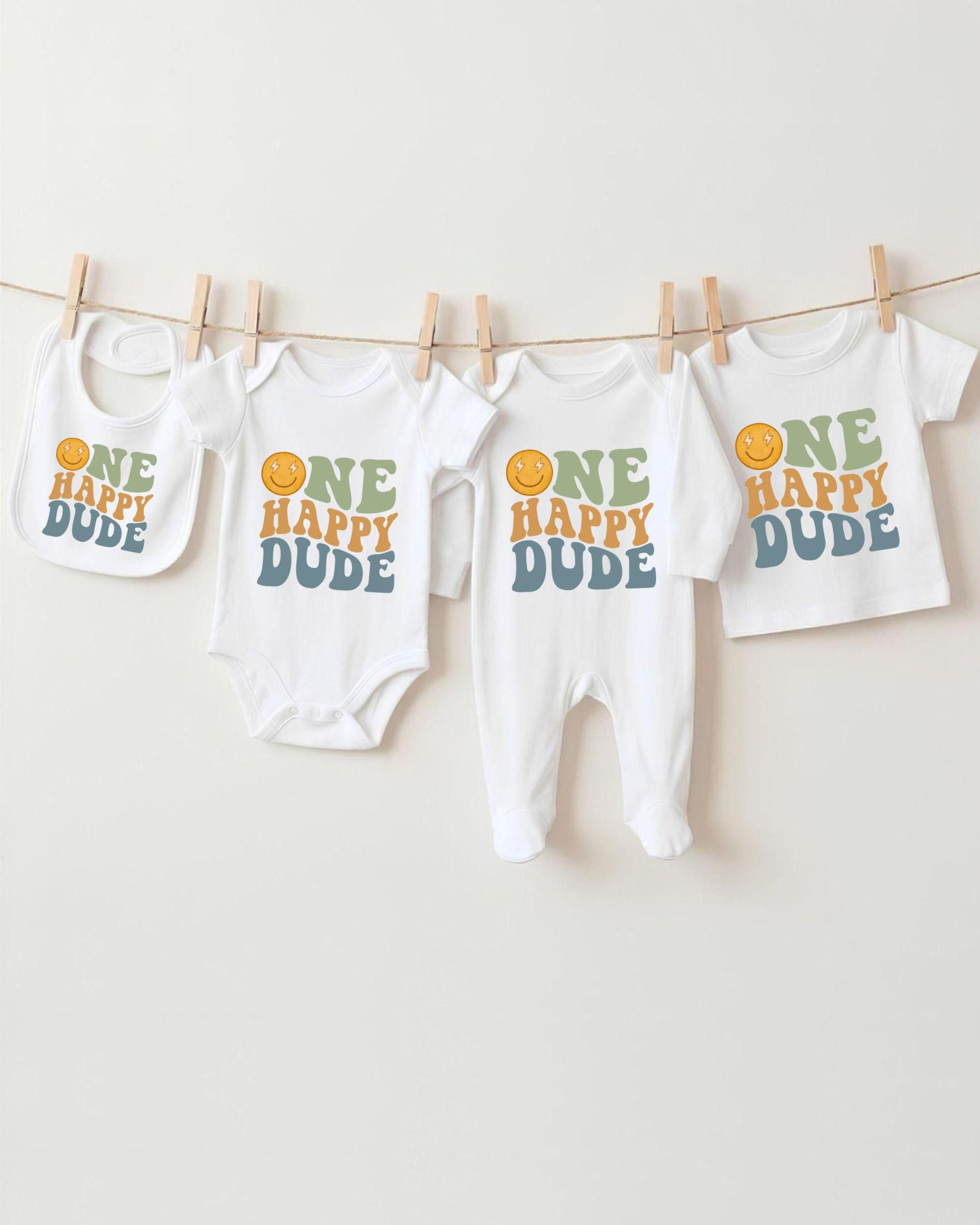 A collection of baby clothes, including onesies and bibs, hanging on a clothesline.