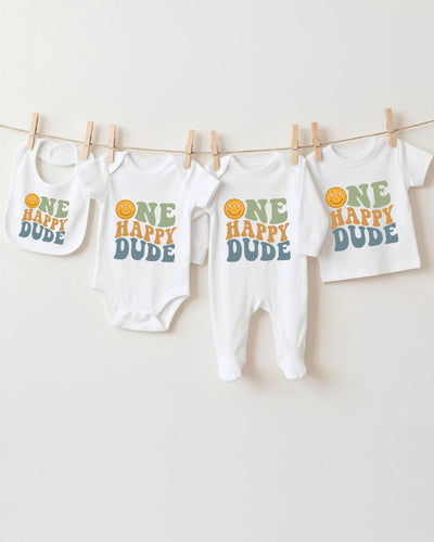A collection of baby clothes, including bodysuits and bibs, hanging on a clothesline.