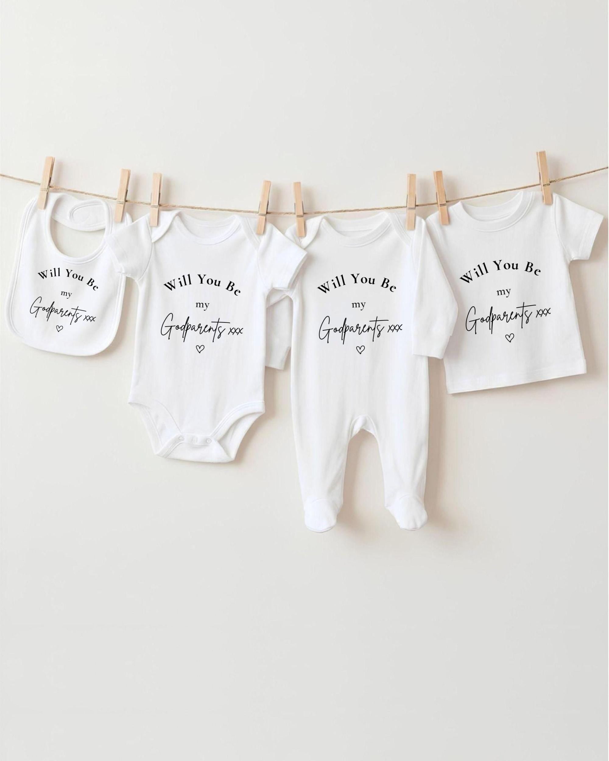 A row of four white baby clothes hanging on a clothesline, each with a different text message printed on it.