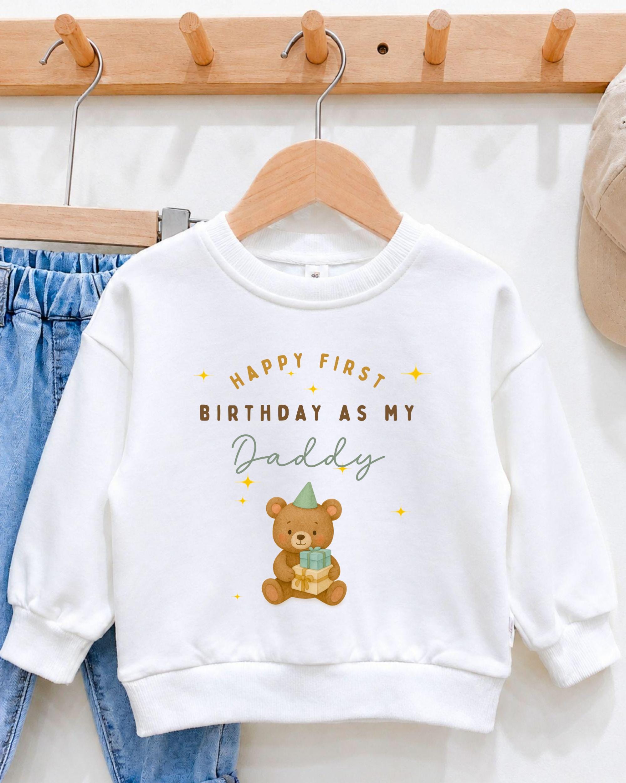 A white sweatshirt with a teddy bear graphic and text that says "Happy first birthday as my Daddy".