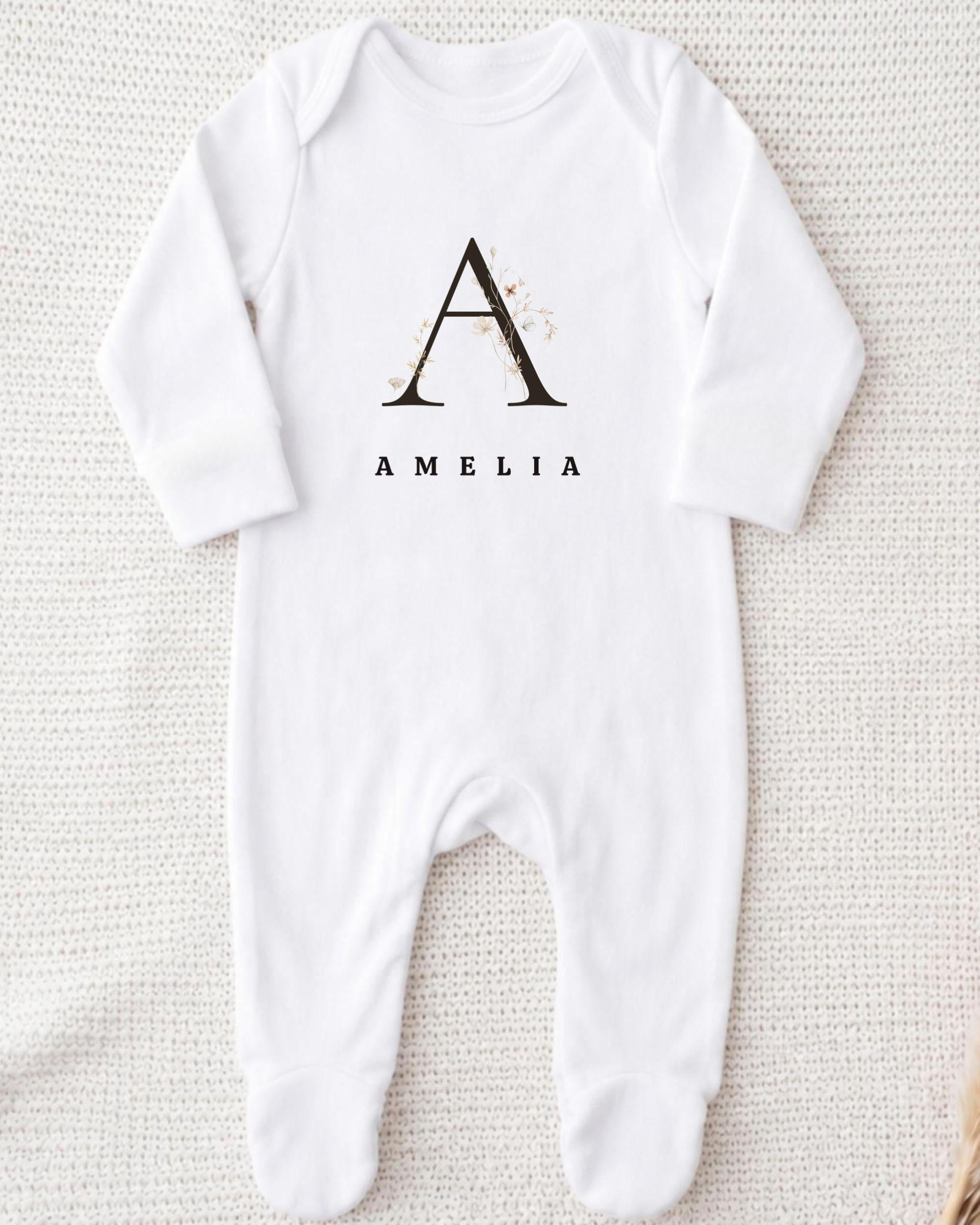 A white onesie with a monogrammed letter "A" and the name "Amelia" printed on it.