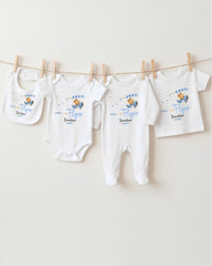 A row of four white baby clothes, including onesies and bibs, hanging on a clothesline.