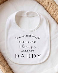 A white bib with a message printed on it, placed on a white cloth.