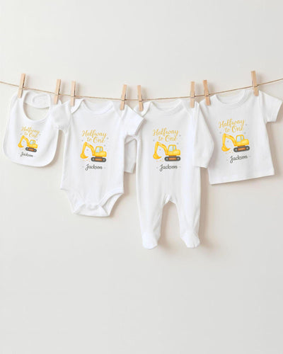 A collection of baby clothes, including onesies and bibs, hanging on a clothesline.