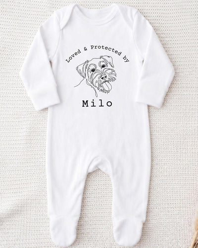 A white bodysuit with a black line drawing of a dog's face and the text "Loved & Protected by" above it, along with the name "Milo" below the drawing.