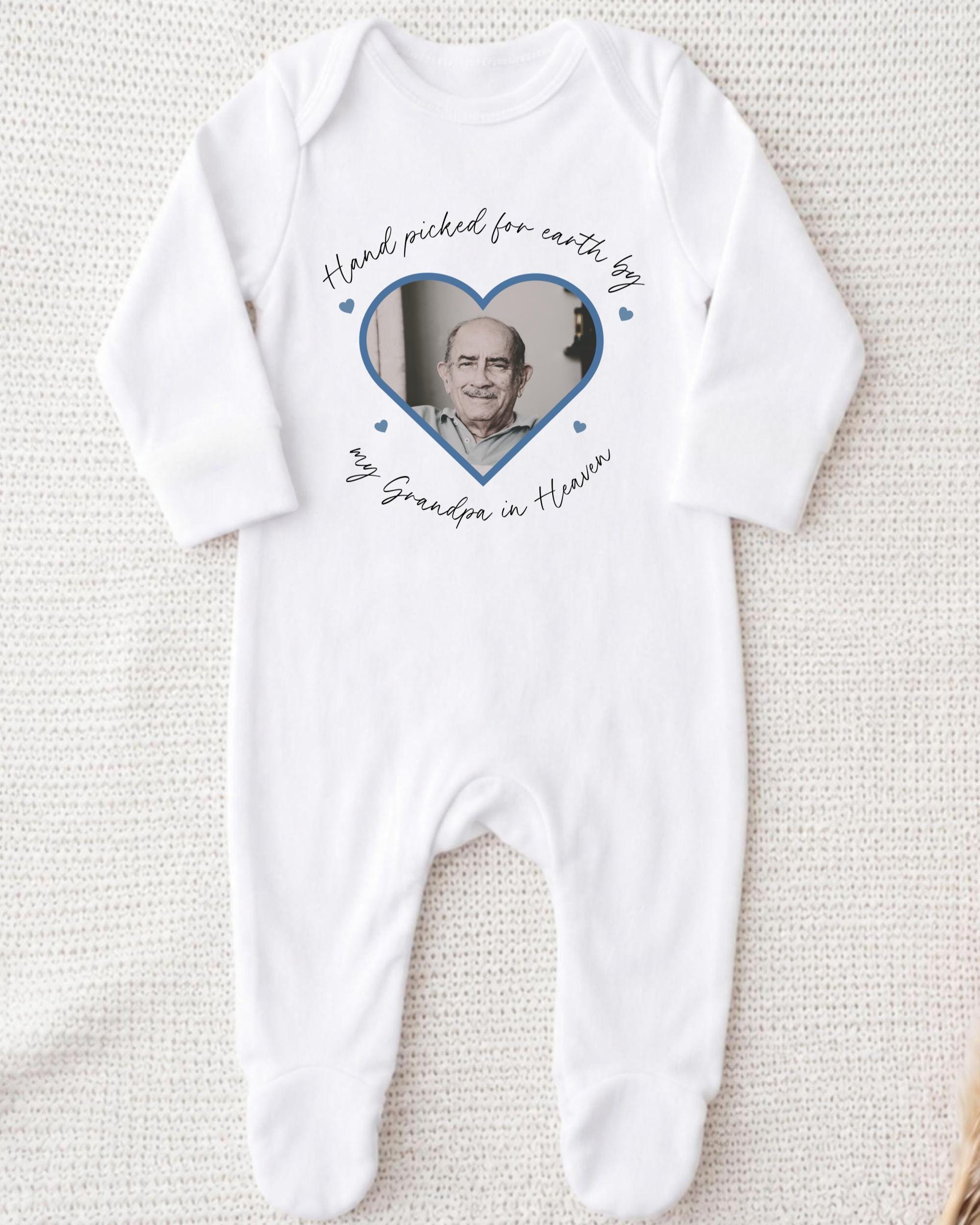 A white onesie with a heart-shaped photo of an older man and the text "Hand picked for earth by my Grandpa in Heaven" printed on it.