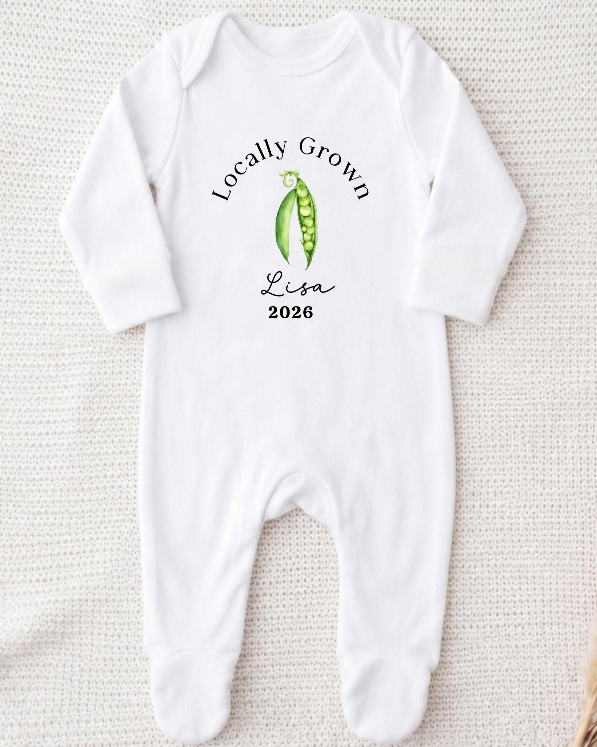 A white onesie with a graphic of peas and the text "Locally Grown Lisa 2026" printed on it.
