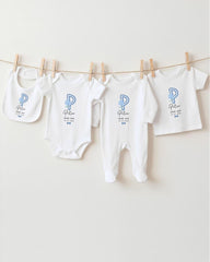 A row of white baby clothes with a blue letter "P" on them, hanging on a clothesline.
