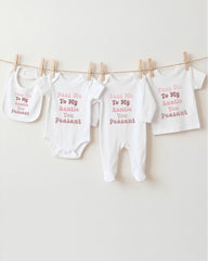 A row of four white baby clothes hanging on a clothesline, each with a different message printed on it.
