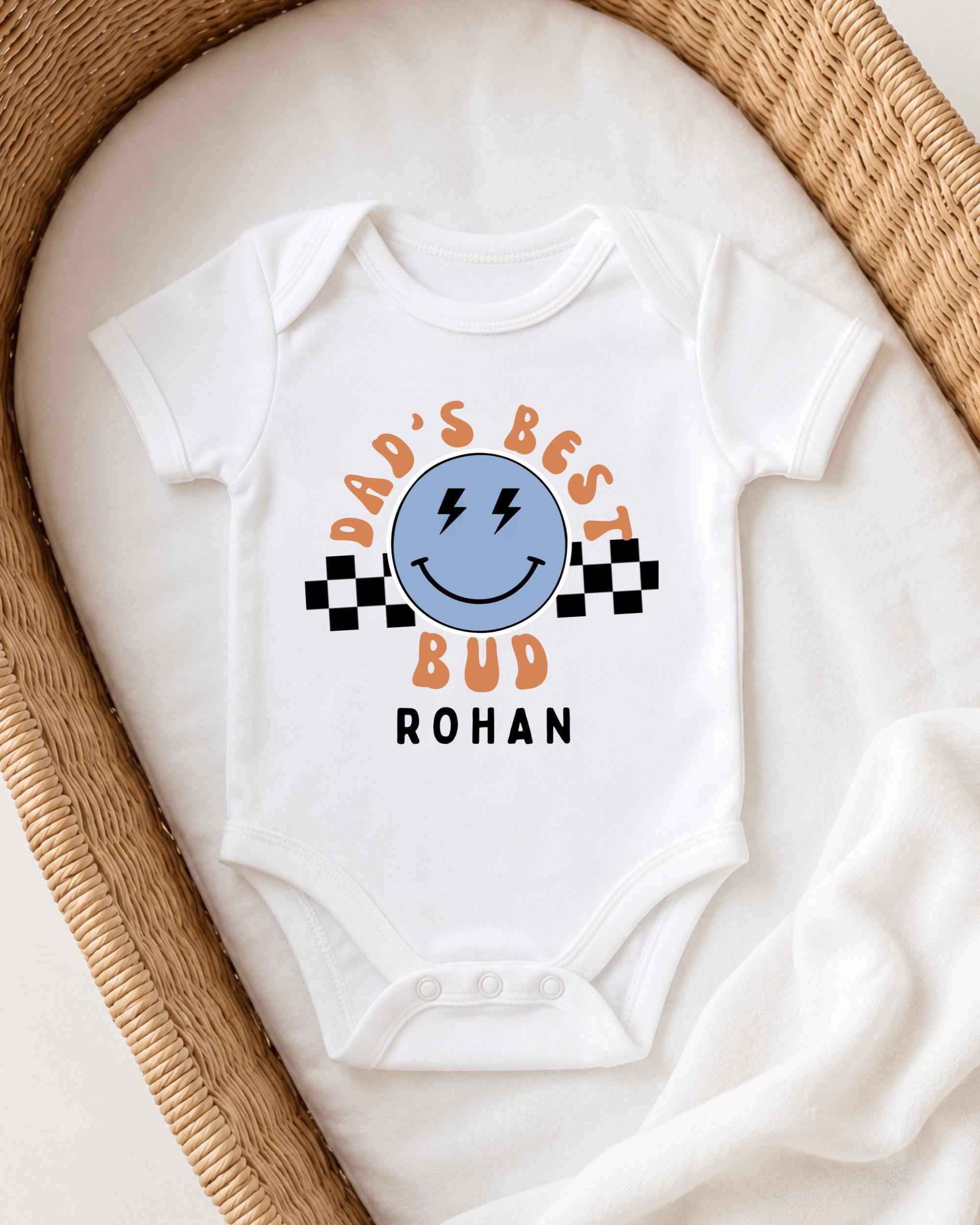 A white onesie with a graphic design on it, placed in a woven basket.