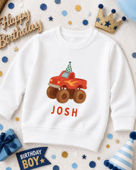 A white sweatshirt with a red truck and a birthday hat on it, surrounded by party decorations and a birthday banner.