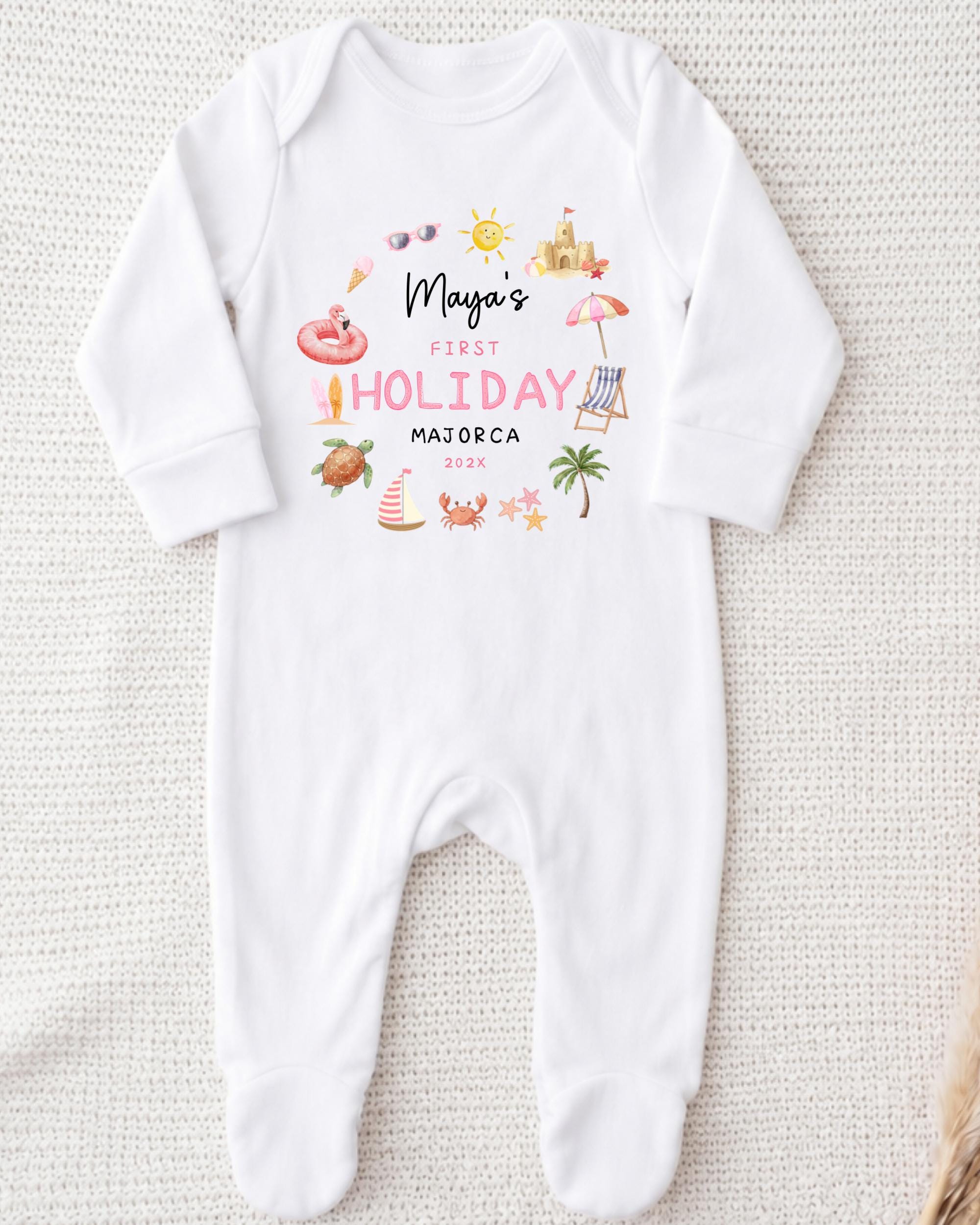 A white onesie with a personalized text and illustrations on it, placed on a white surface.