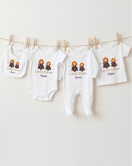 A row of four white baby clothes, including onesies and pajamas, hanging on a clothesline.
