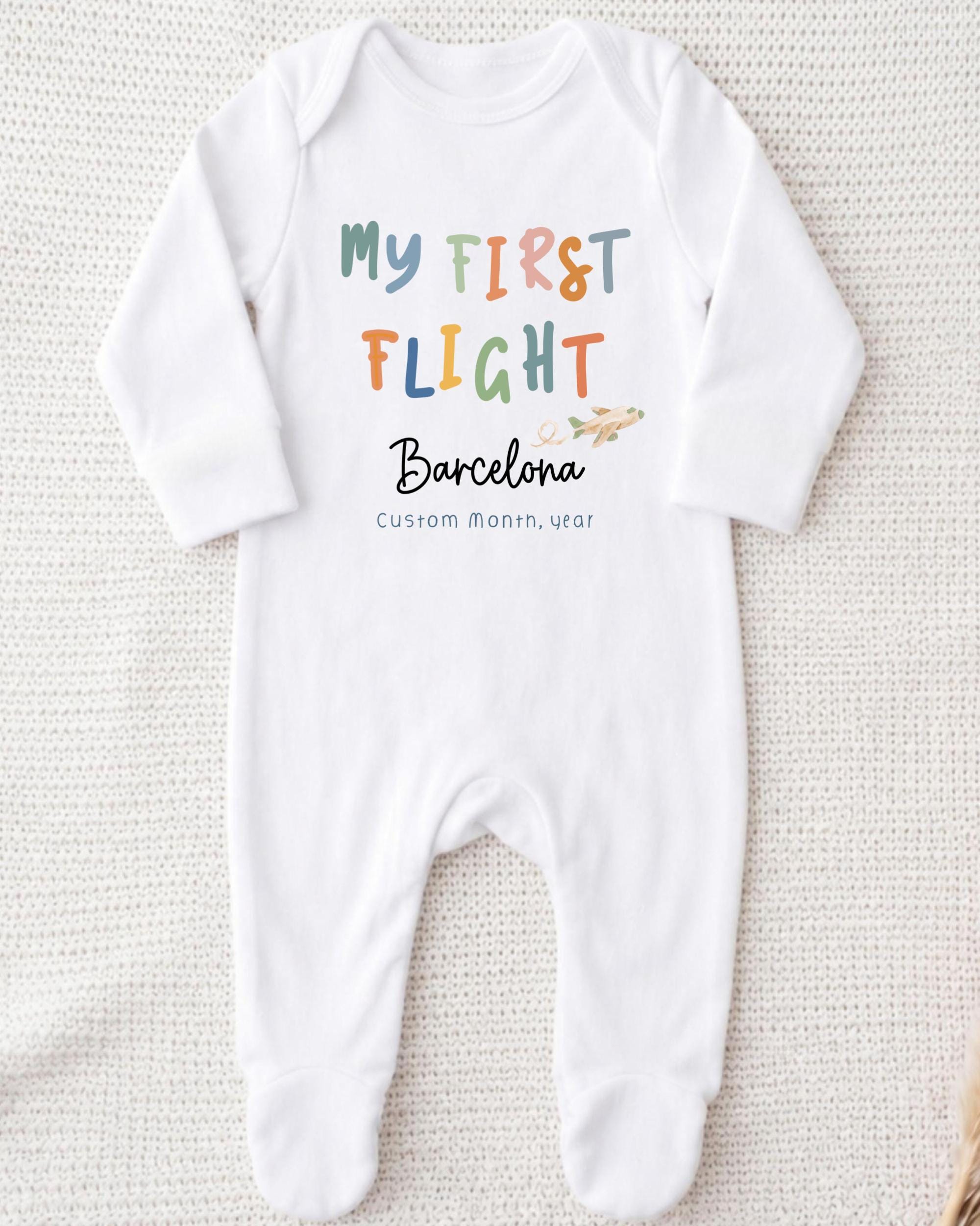 A white onesie with text and an illustration of a plane on it.