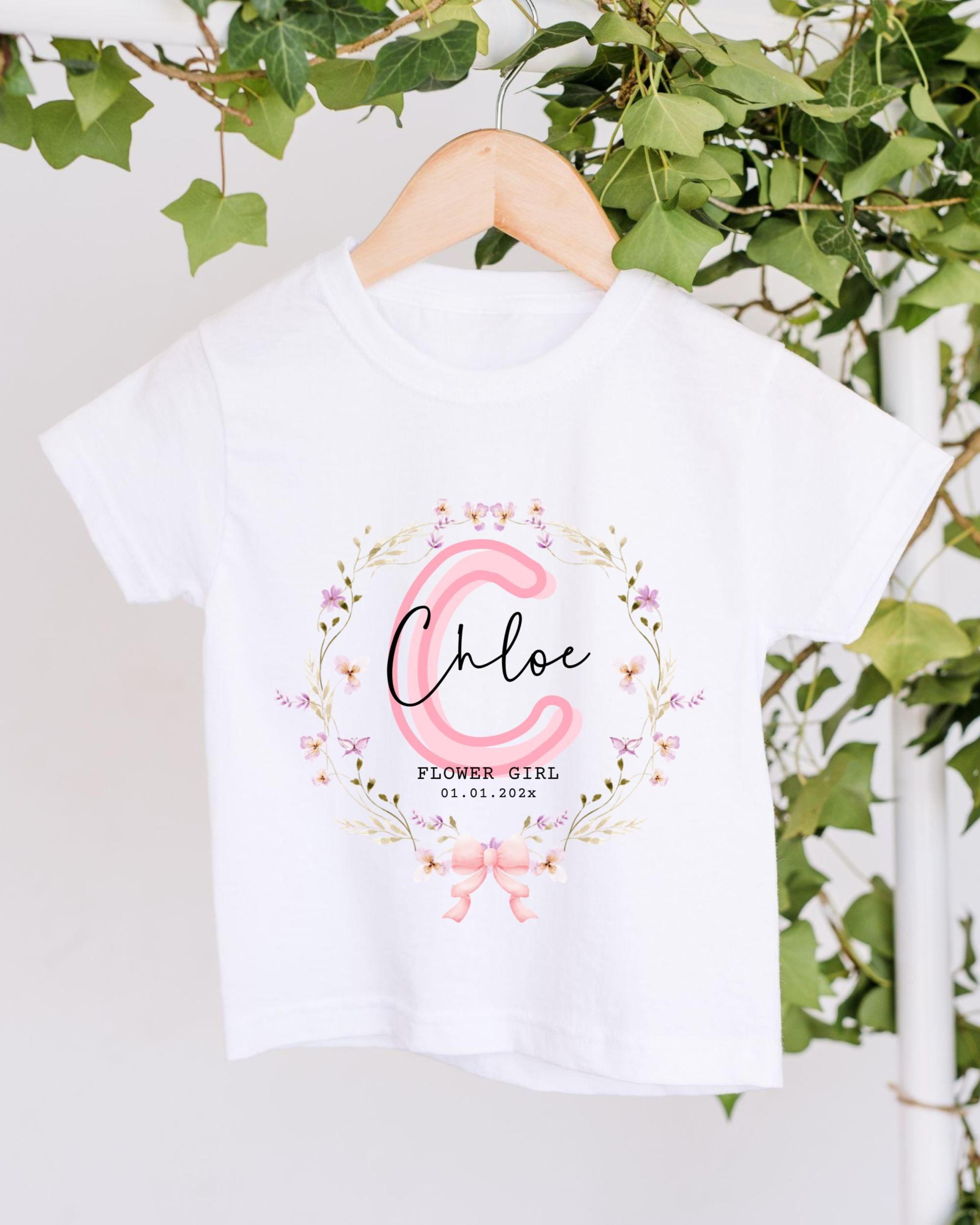 A white t-shirt with a floral design and the name "Chloe" printed on it, hanging on a wooden hanger.