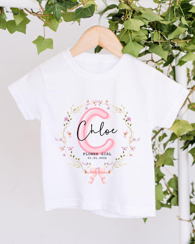 A white t-shirt with a floral design and the name "Chloe" printed on it, hanging on a wooden hanger.