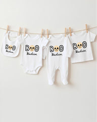 A collection of white baby clothes, including onesies and bibs, with the name "Hudson" printed on them. The clothes are hanging on a clothesline, with the name "BOO" printed on them.