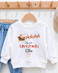 A white sweatshirt with a Christmas-themed design hanging on a wooden hanger.