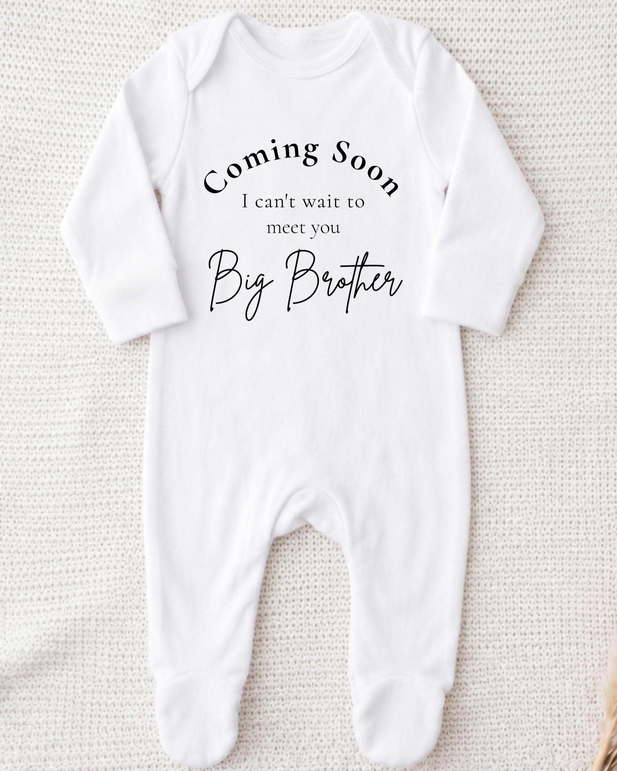 A white onesie with text that says "Coming Soon I can't wait to meet you Big Brother".