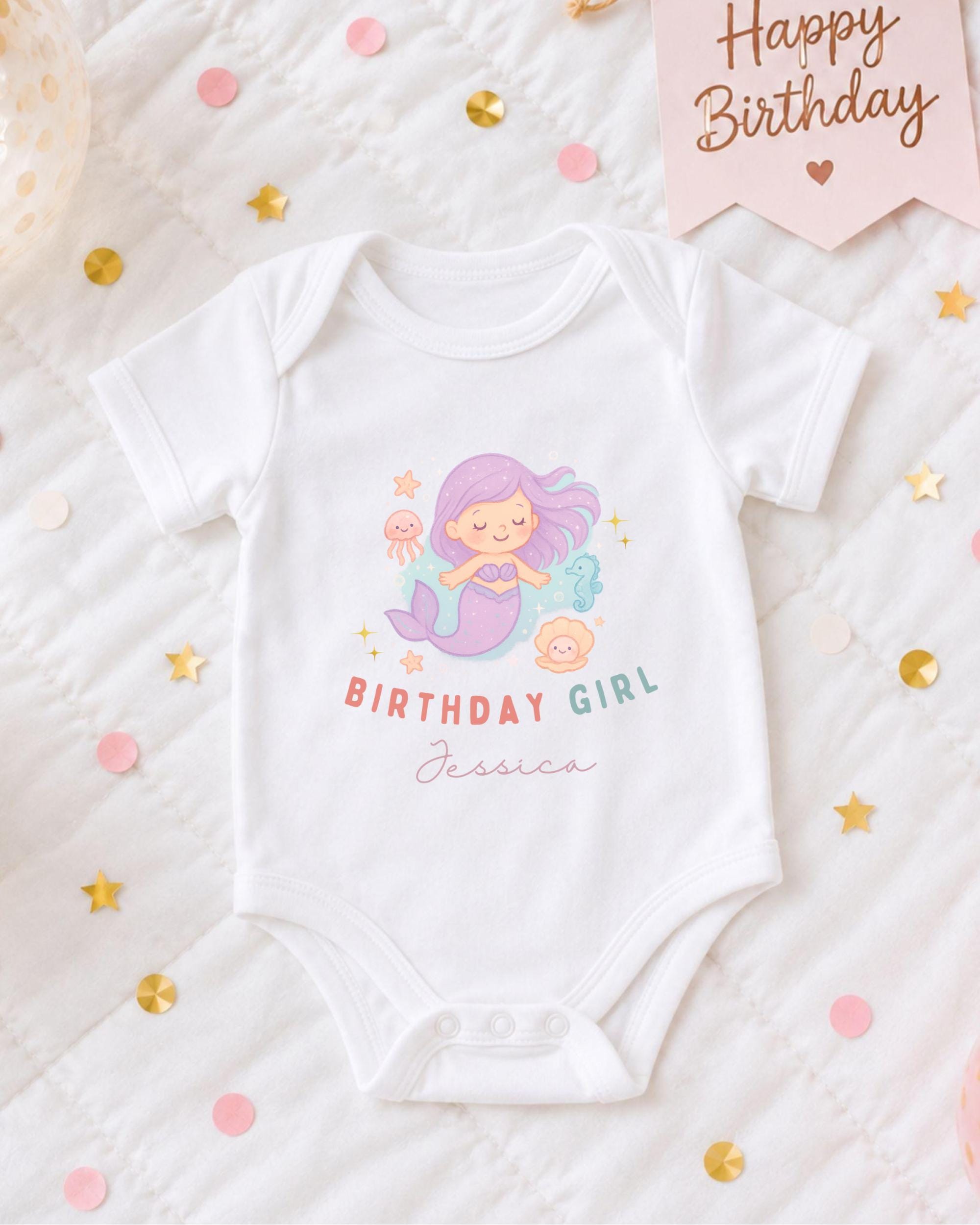 A white onesie with a mermaid design and the text "Birthday Girl Jessica" printed on it, along with confetti and a birthday card.