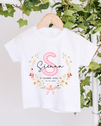 A white t-shirt with a floral design and the name "Siena" printed on it, hanging on a wooden hanger.