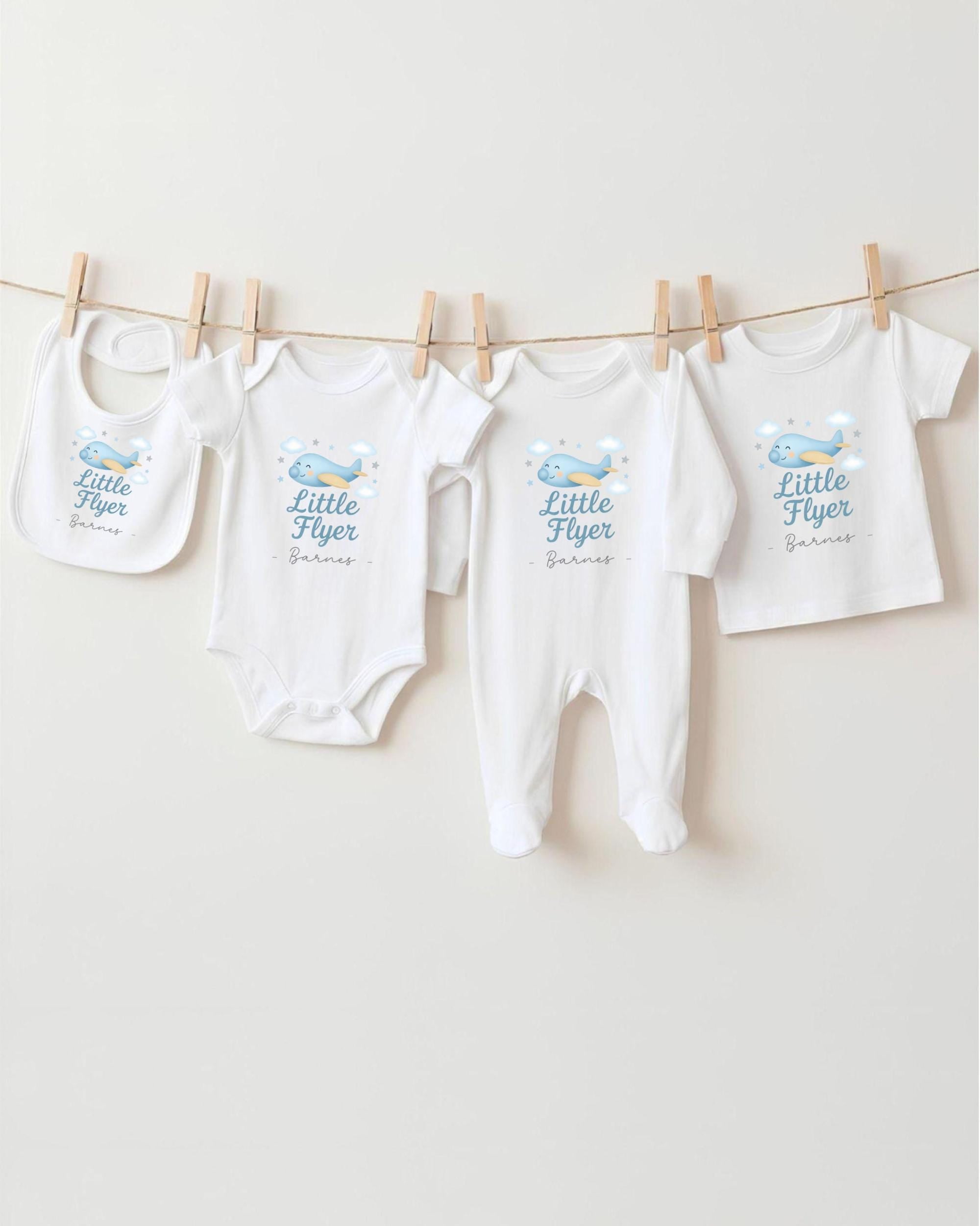 A collection of baby clothes, including onesies and bibs, hanging on a clothesline.