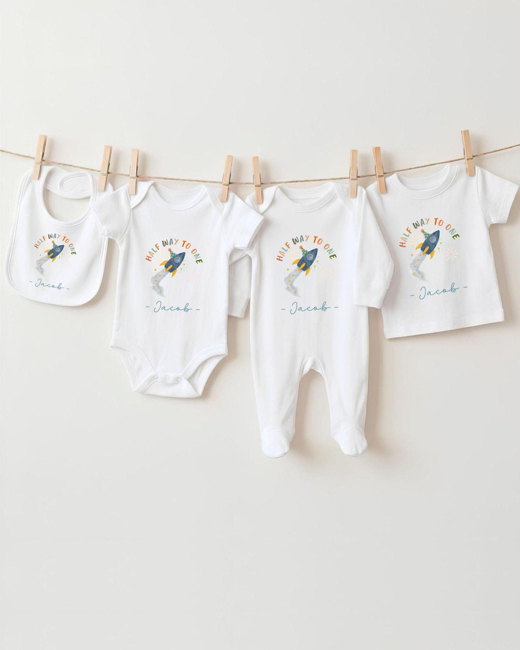 A collection of baby clothes, including onesies and bibs, hanging on a clothesline.
