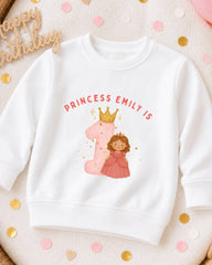 A white sweatshirt with a pink princess and the number 1 printed on it, along with the text "PRINCESS EMILY IS" and a crown.