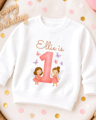 A white sweatshirt with a personalized design featuring two fairy characters and the number 1.